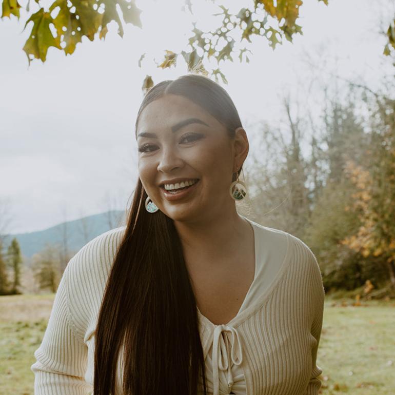 woman wearing ivory acrylic earring with mountain cut out and abalone inlay from copper canoe woman