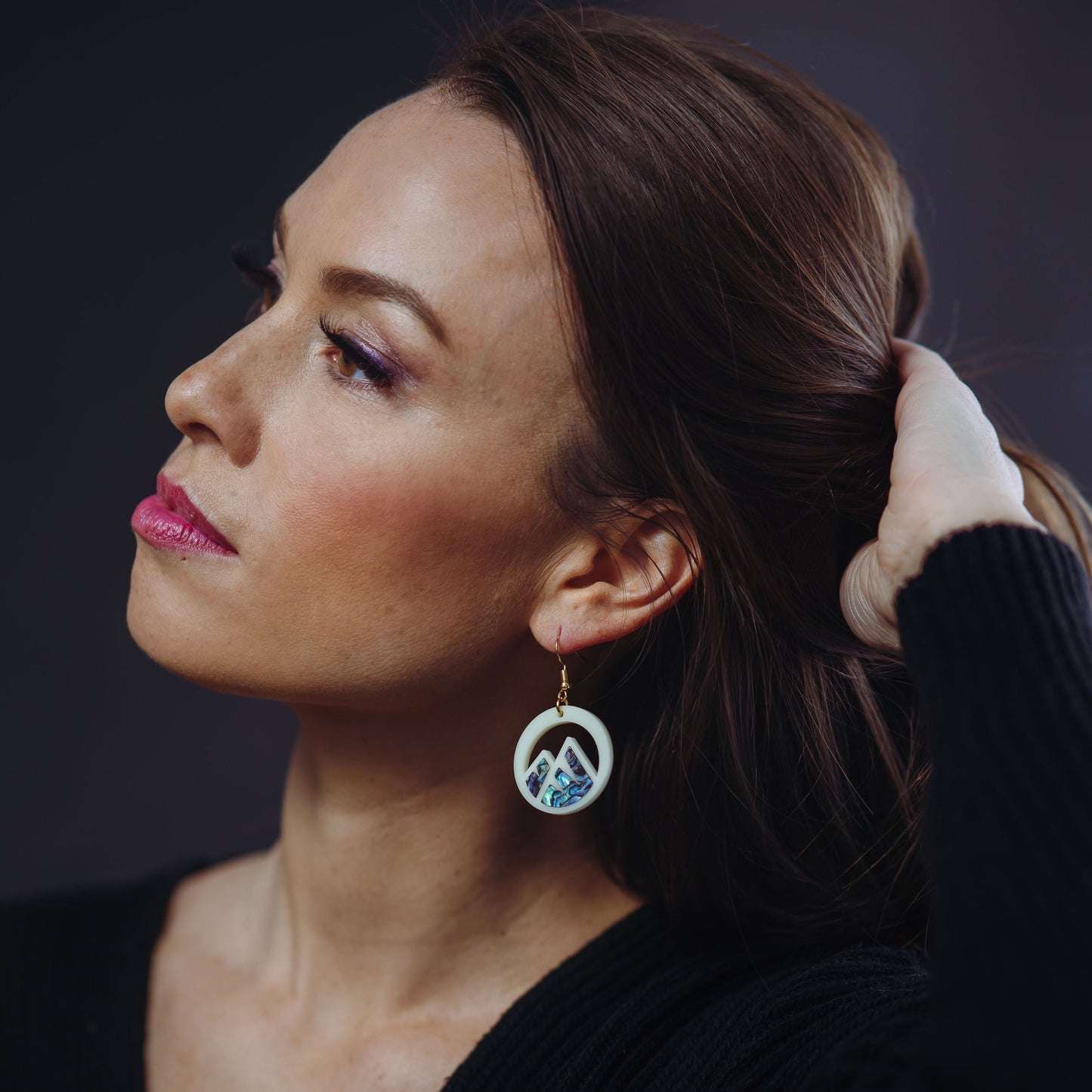 woman wearing ivory acrylic earring with mountain cut out and abalone inlay from copper canoe woman