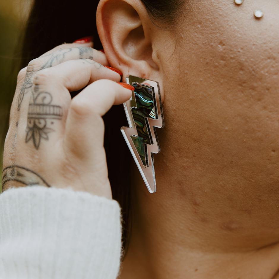 Close up of silver acrylic lightning bolt earring with abalone inlay from Copper Canoe Woman