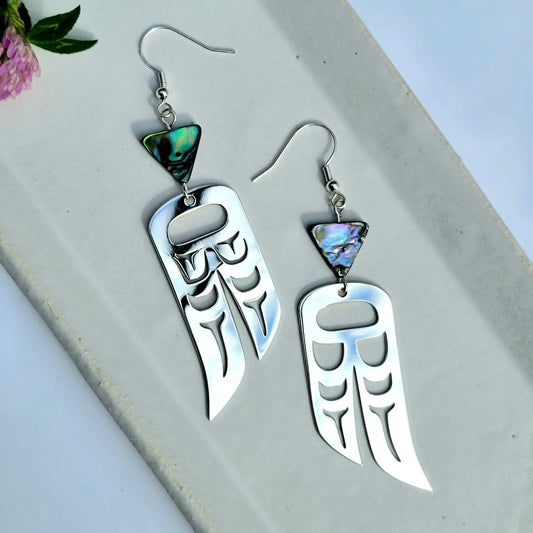 Sterling Silver earrings of wings in formline art: one eagle, one raven. Topped with triangle abalone beads from copper canoe woman