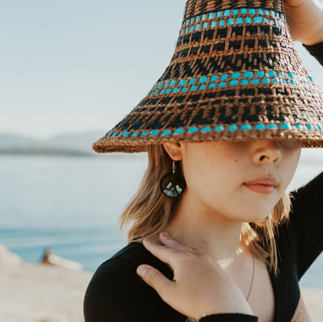 young woman wearing black acrylic earring with mountain cut out and abalone inlay from copper canoe woman