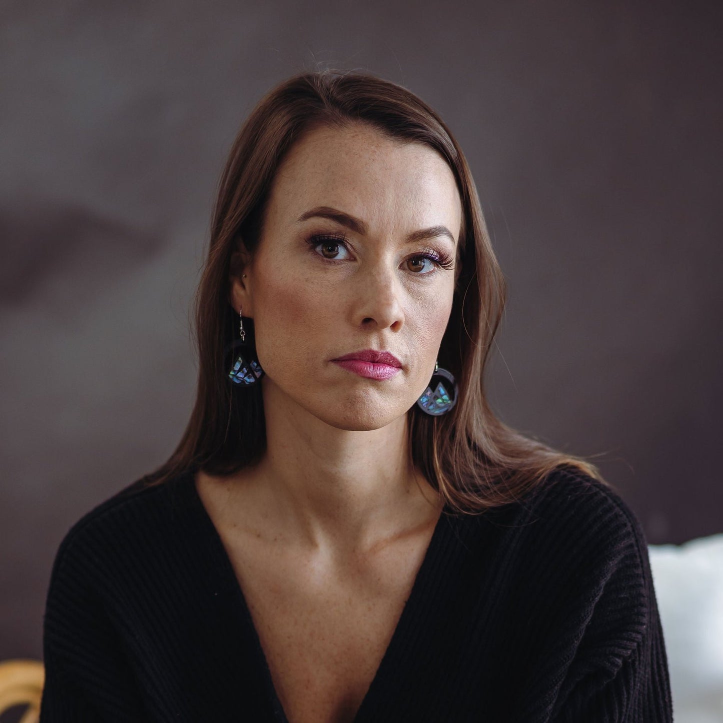 woman wearing black acrylic earring with mountain cut out and abalone inlay from copper canoe woman