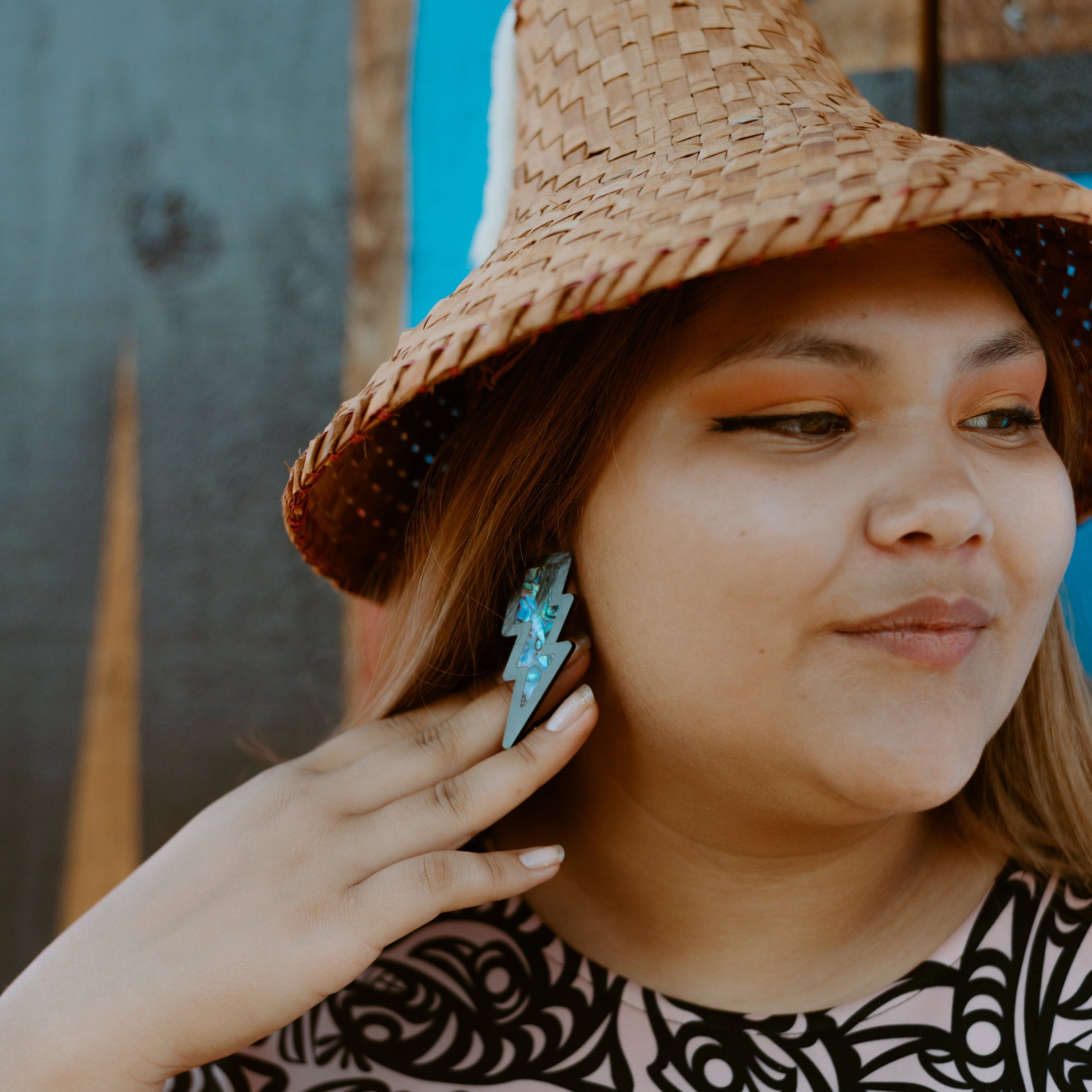 model wearing acrylic black lightning bolt earring with abalone inlay from copper canoe woman. 