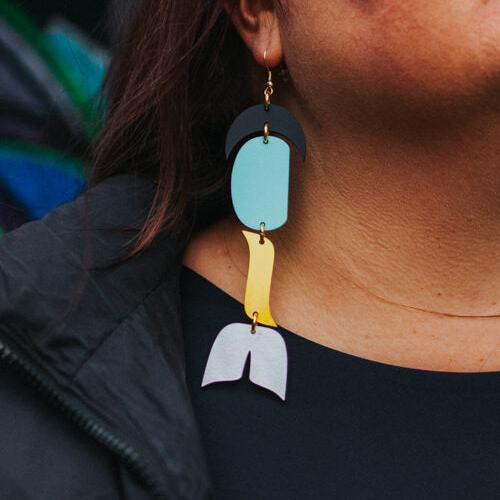 woman wearing abstract formline art in color sequence of black, turquoise, yellow, white from copper canoe woman.