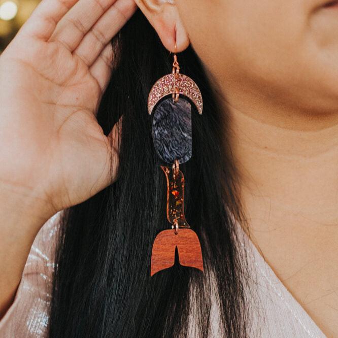 close up of woman wearing abstract formline art in color sequence of rose gold glitter, galaxy purple, copper glitter, and wood from copper canoe woman.