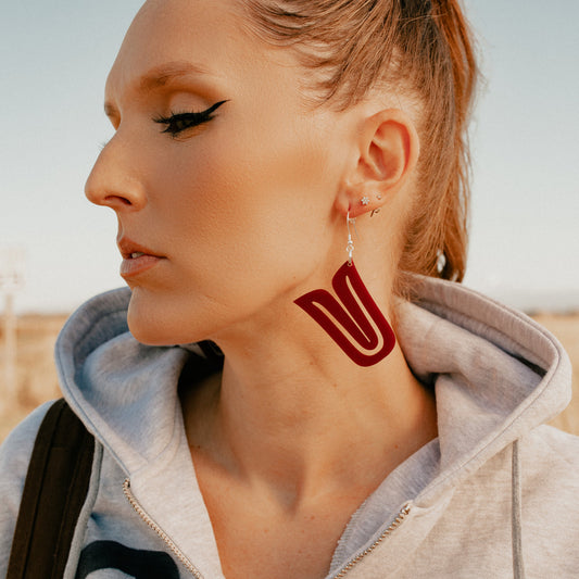 Model in side profile wearing red acrylic "Echoed U" earrings from Copper Canoe Woman.