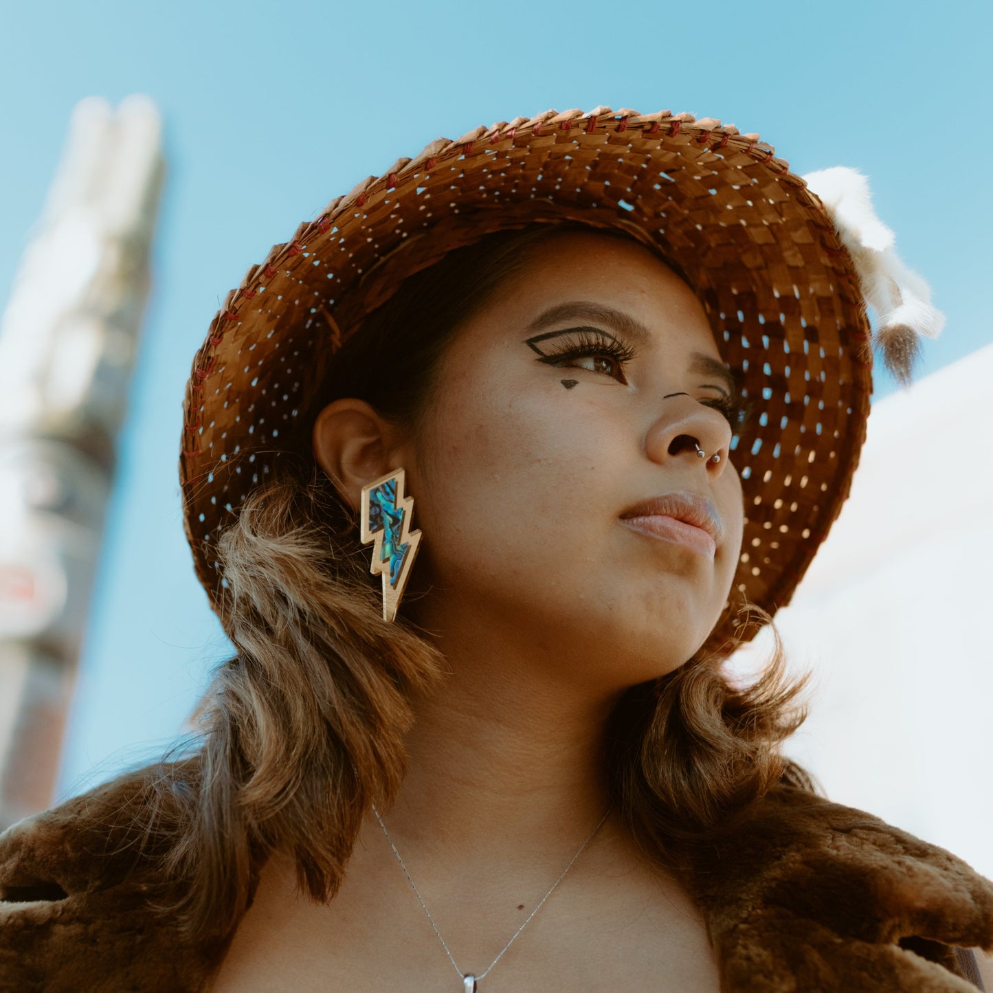 young girl wearing gold acrylic lightning bolt earring with abalone inlay from copper canoe woman