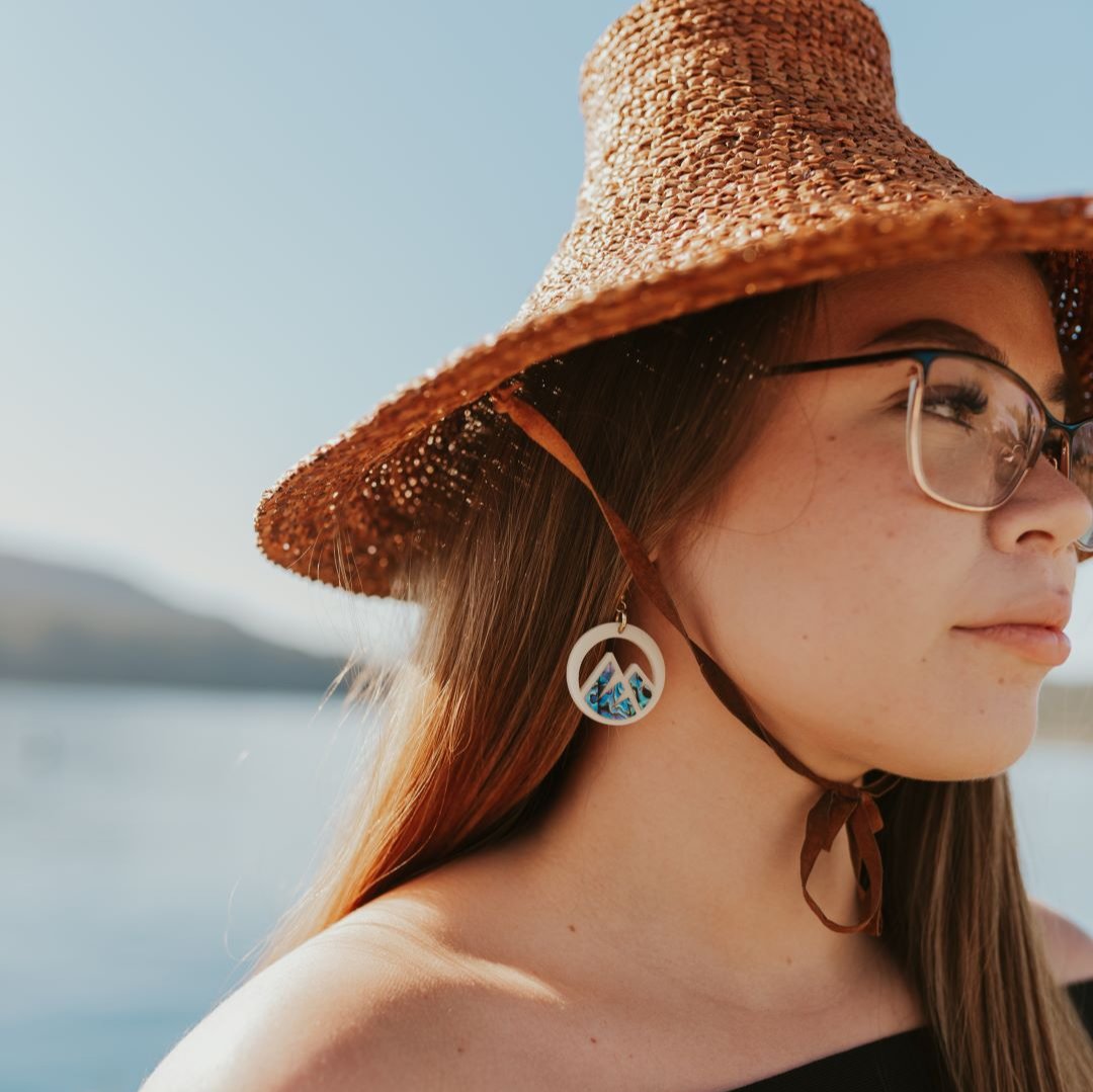 young woman wearing ivory acrylic earring with mountain cut out and abalone inlay from copper canoe woman