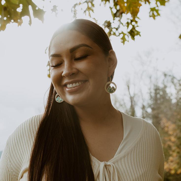 woman wearing ivory acrylic earring with mountain cut out and abalone inlay from copper canoe woman