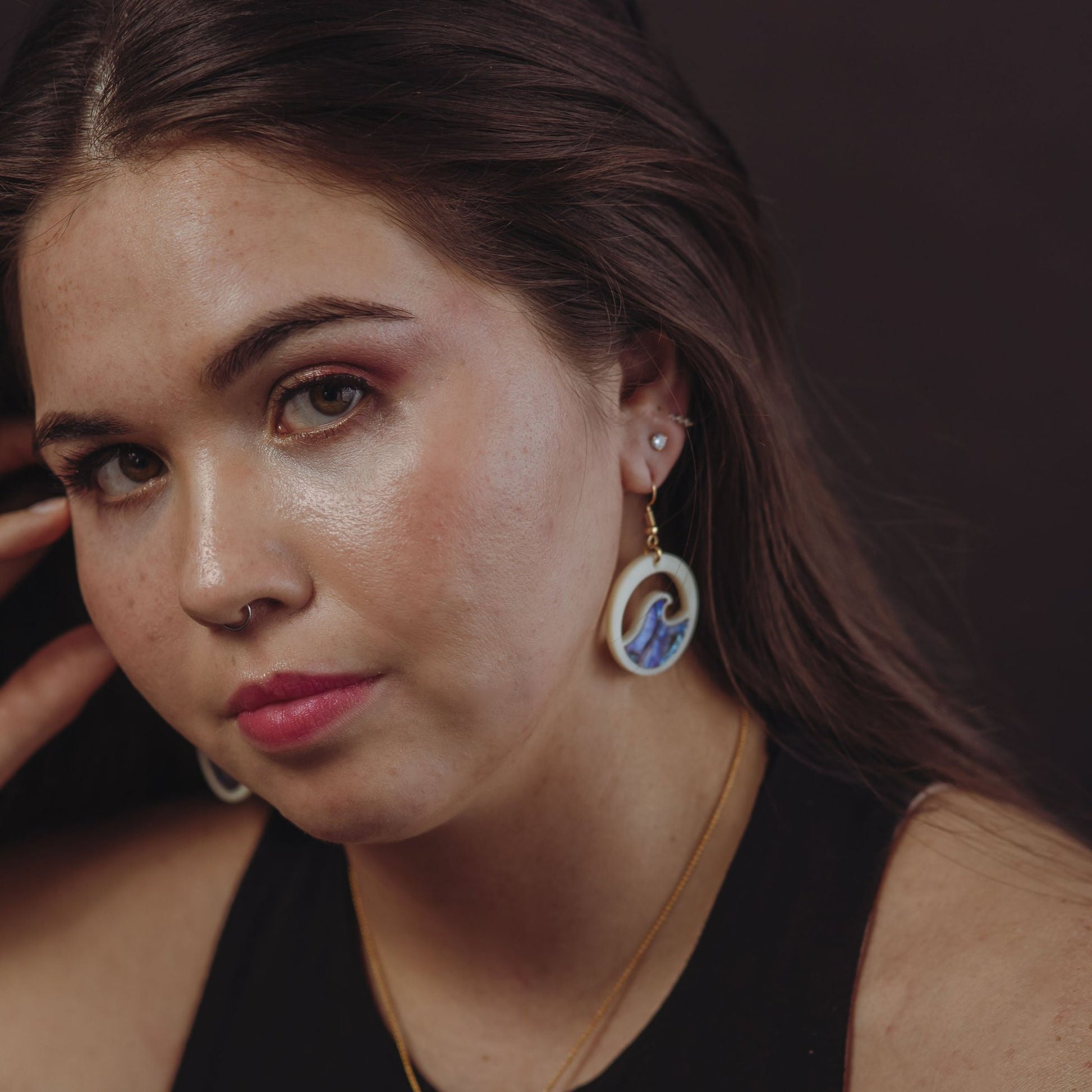 woman wearing ivory acrylic earring with wave cut out and abalone inlay from copper canoe woman