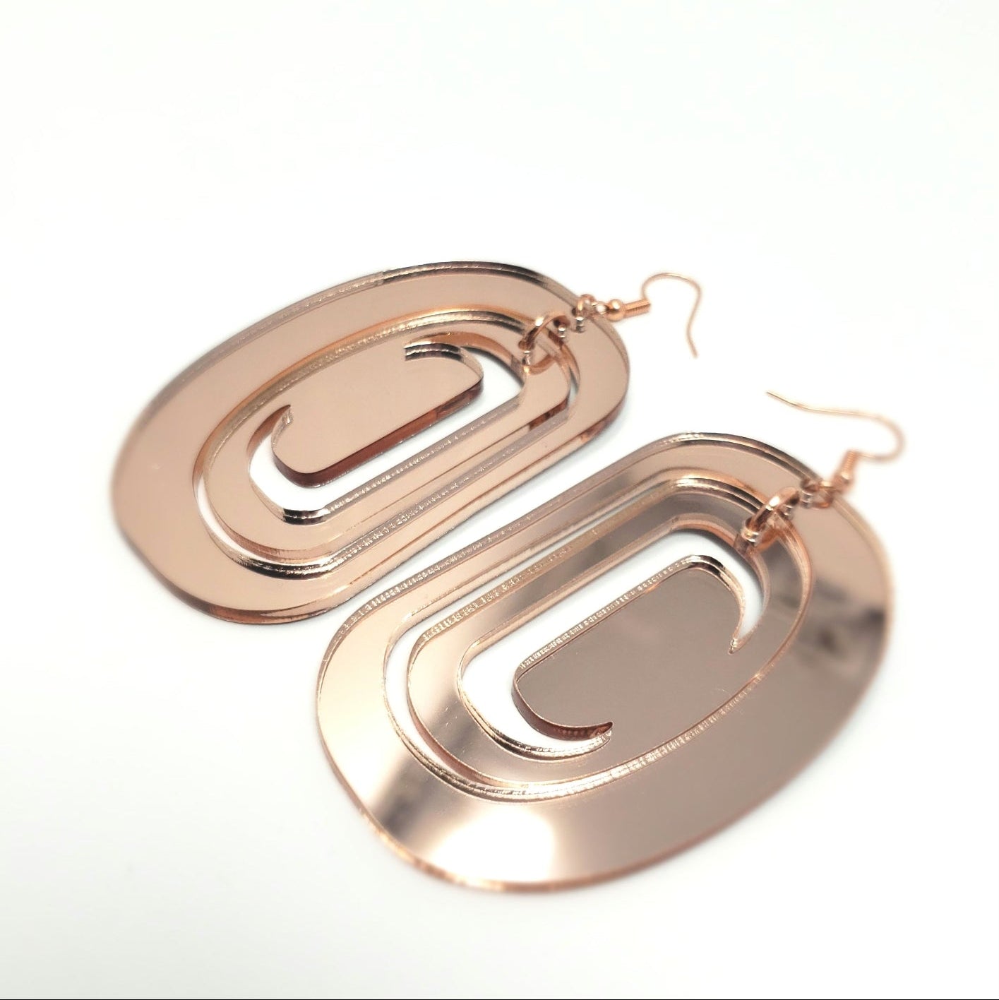 Large ovoid earring from Copper Canoe Woman in rose gold mirror acrylic with crescent cutout.