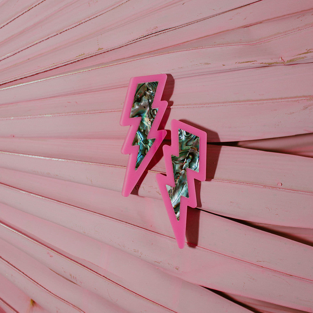 Lightning bolt earrings from Copper Canoe Woman in hot pink acrylic with abalone inlay.