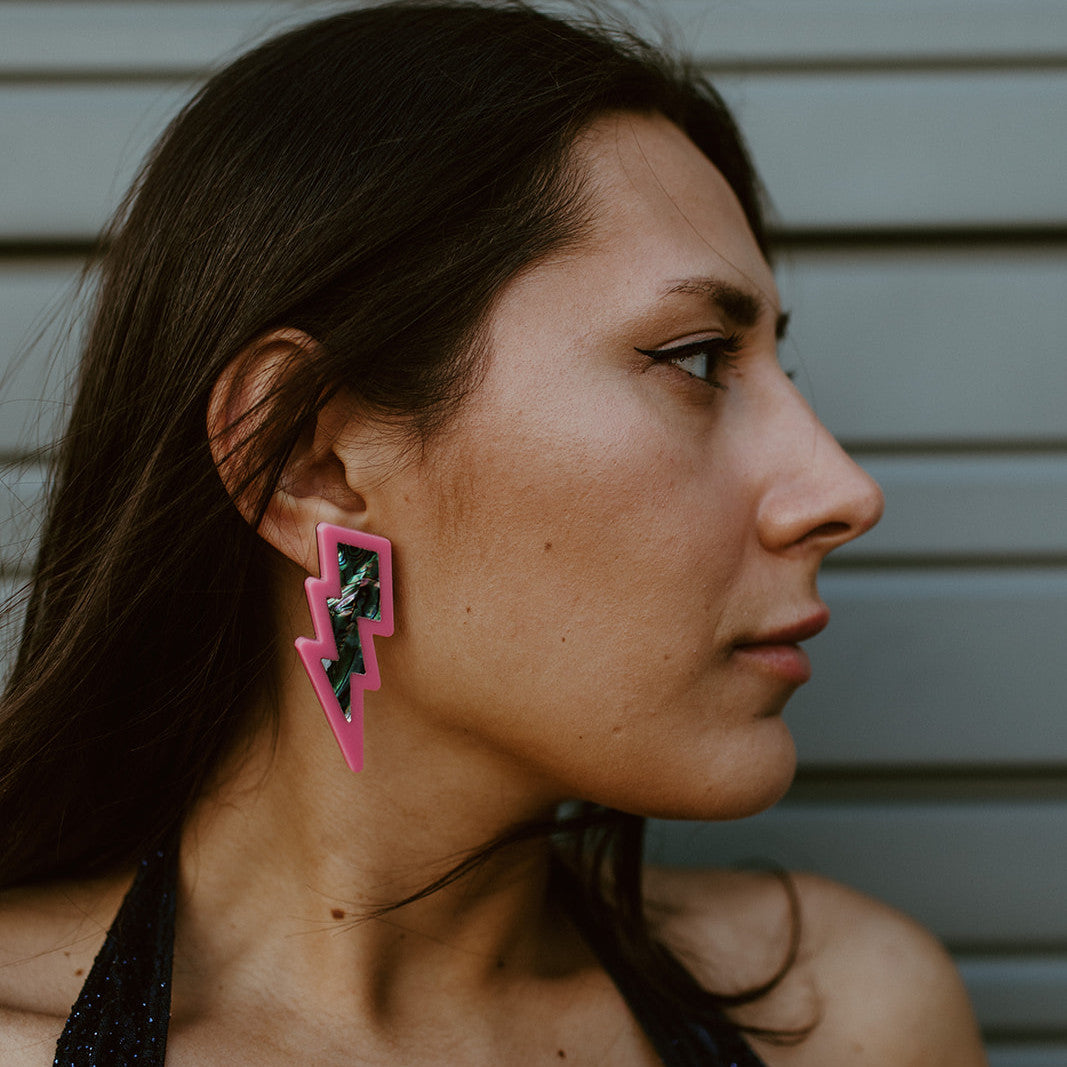 Model in profile wearing hot pink lightning bolt earrings from Copper Canoe Woman.