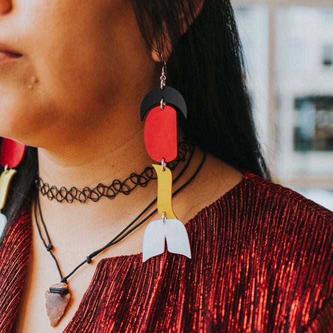 close up of woman wearing abstract formline art in color sequence of black, red, yellow, white from copper canoe woman.