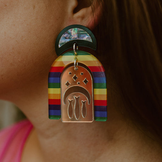 Closeup of model wearing medium pride rainbow post earring from Copper Canoe Woman.