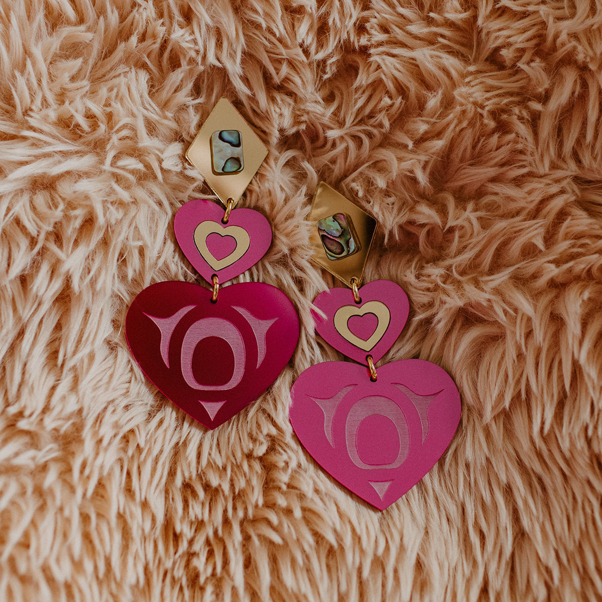 A pair of Copper Canoe Woman monochrome majesty earrings in hot pink acrylic.