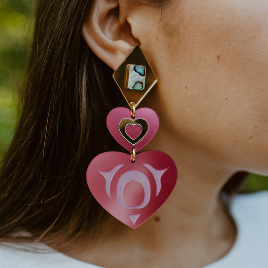 Closeup of model wearing monochrome majesty earrings from Copper Canoe Woman in hot pink acrylic.