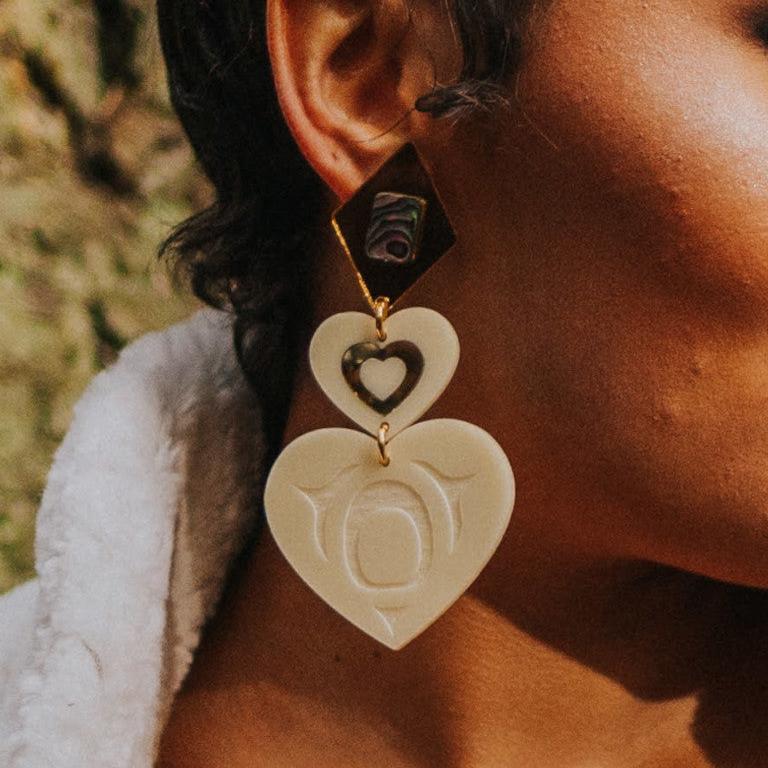 Closeup of model wearing monochrome majesty earring from Copper Canoe Woman in ivory color acrylic.