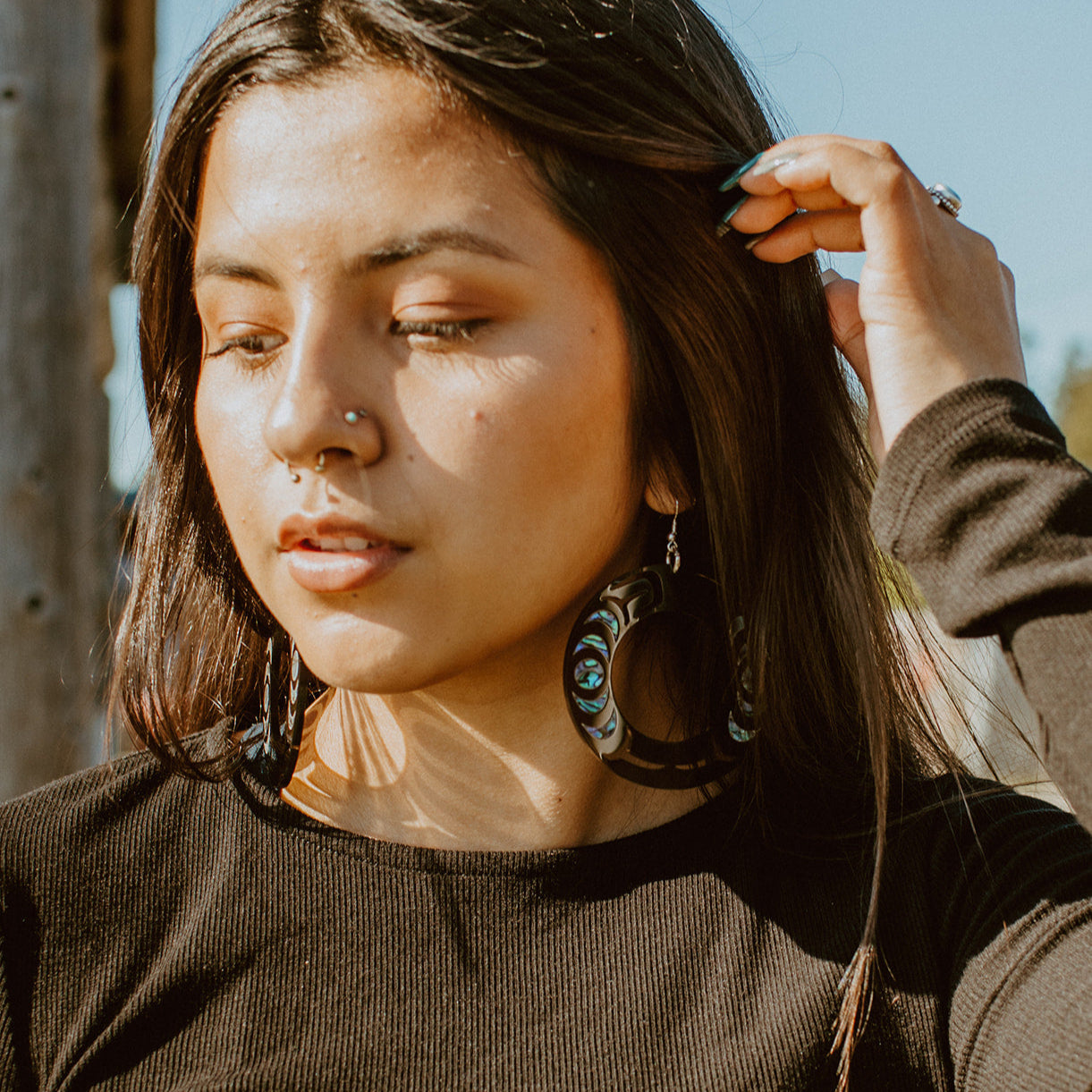 Woman wearing a Nala Hoop earring from Copper Canoe Woman in black acrylic.