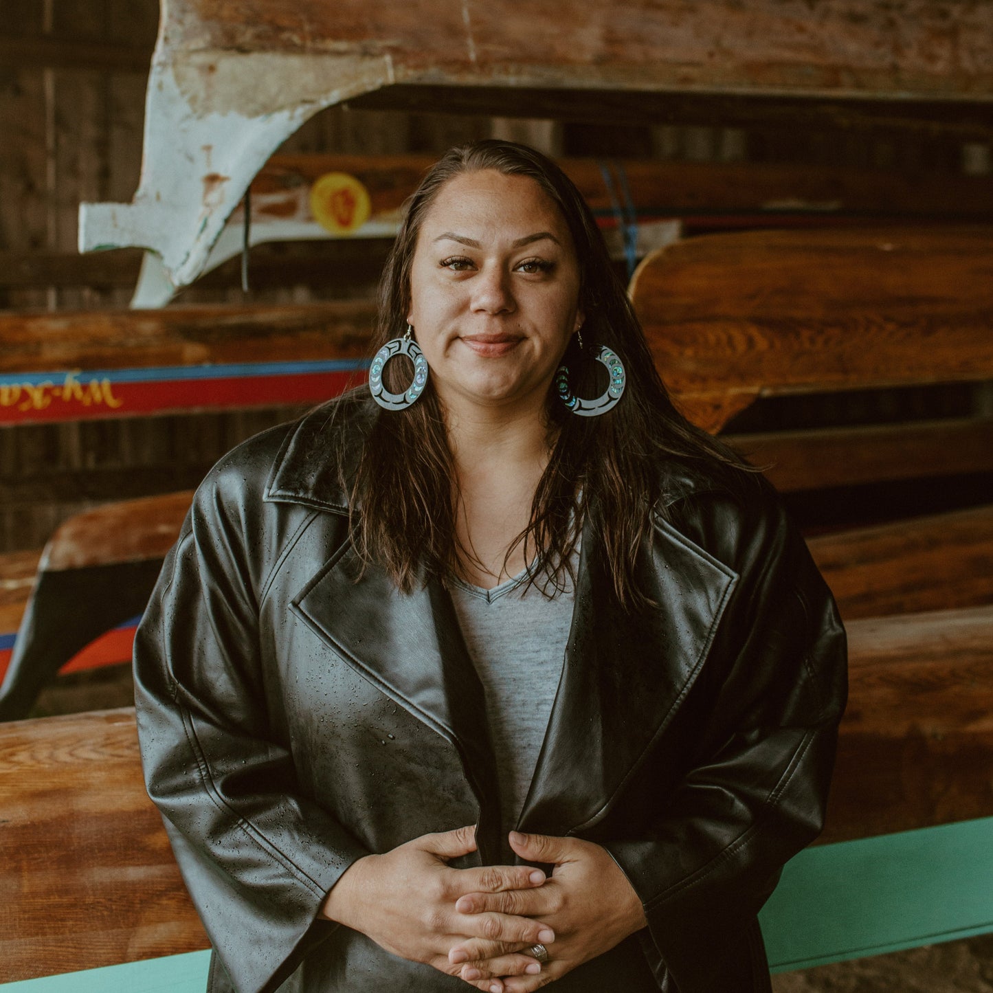 A woman faces the camera wearing a pair of black Nala Hoop earrings from Copper Canoe Woman.