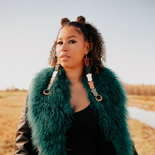 A model stands in a field wearing Copper Canoe Woman's "Opulence Flow" earrings from Copper Canoe Woman.