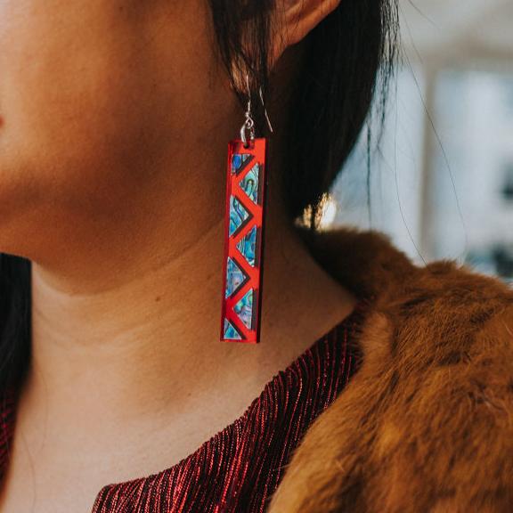 close up of woman wearing red mirror long rectangle warrior spirit earring with triangle zig zag abalone inlay from copper canoe woman