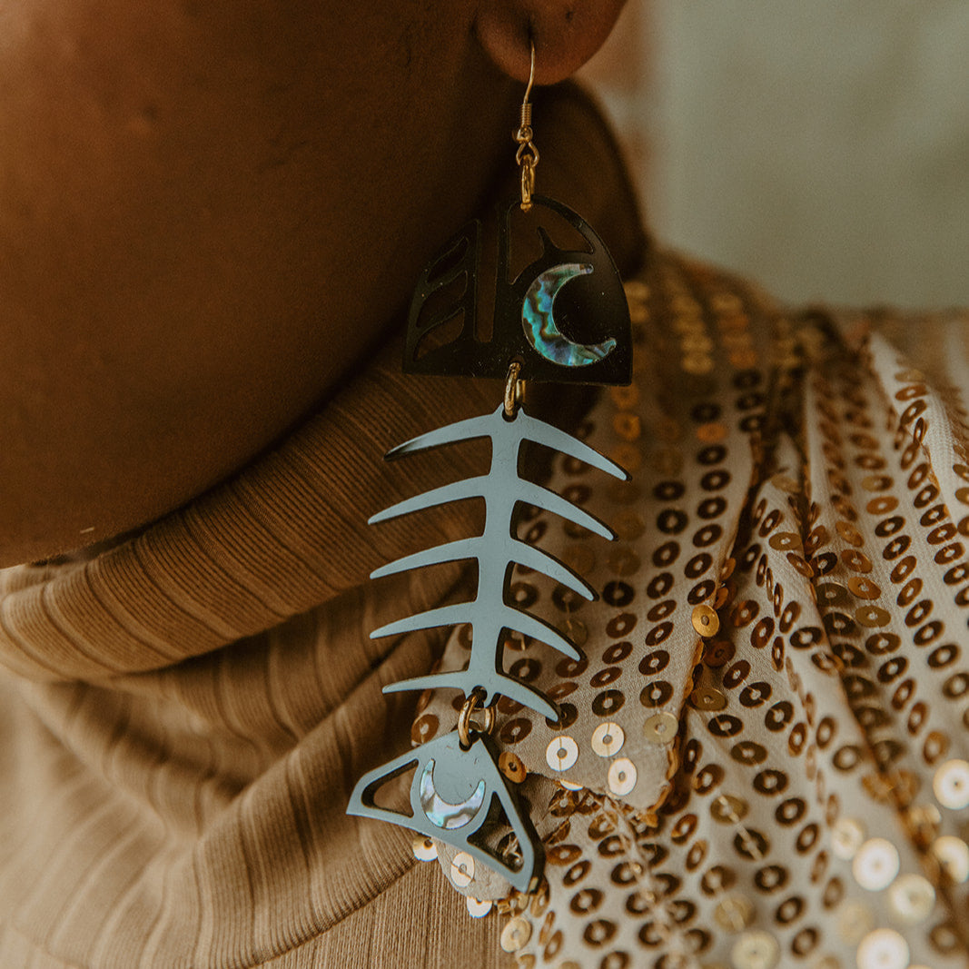 Closeup of model wearing the black acrylic Medium Salmon Ghost earring from Copper Canoe Woman.