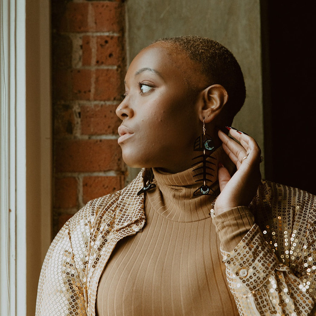 Model wearing the black acrylic Medium Salmon Ghost earring from Copper Canoe Woman.