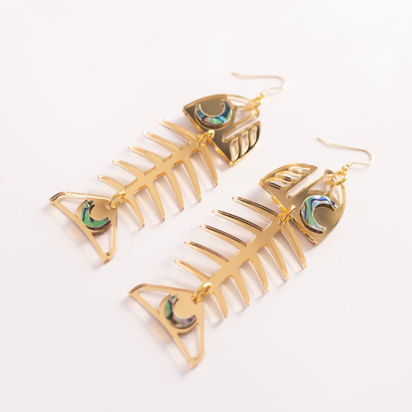 A pair of Medium Salmon Ghost earrings from Copper Canoe Woman in gold mirror acrylic.