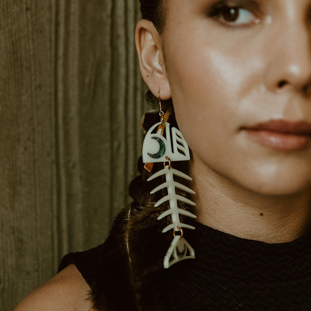 Closeup of model wearing the ivory acrylic Medium Salmon Ghost earring from Copper Canoe Woman.