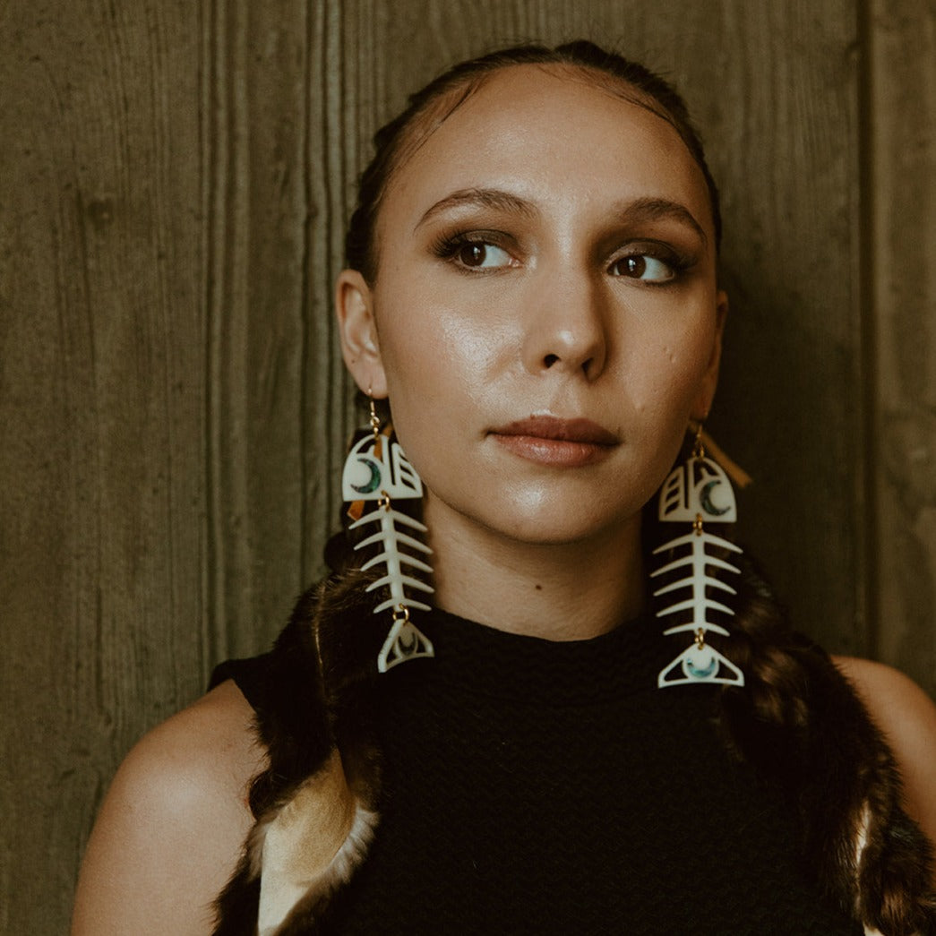 A model wearing the Medium Salmon Ghost earring from Copper Canoe Woman in ivory acrylic.