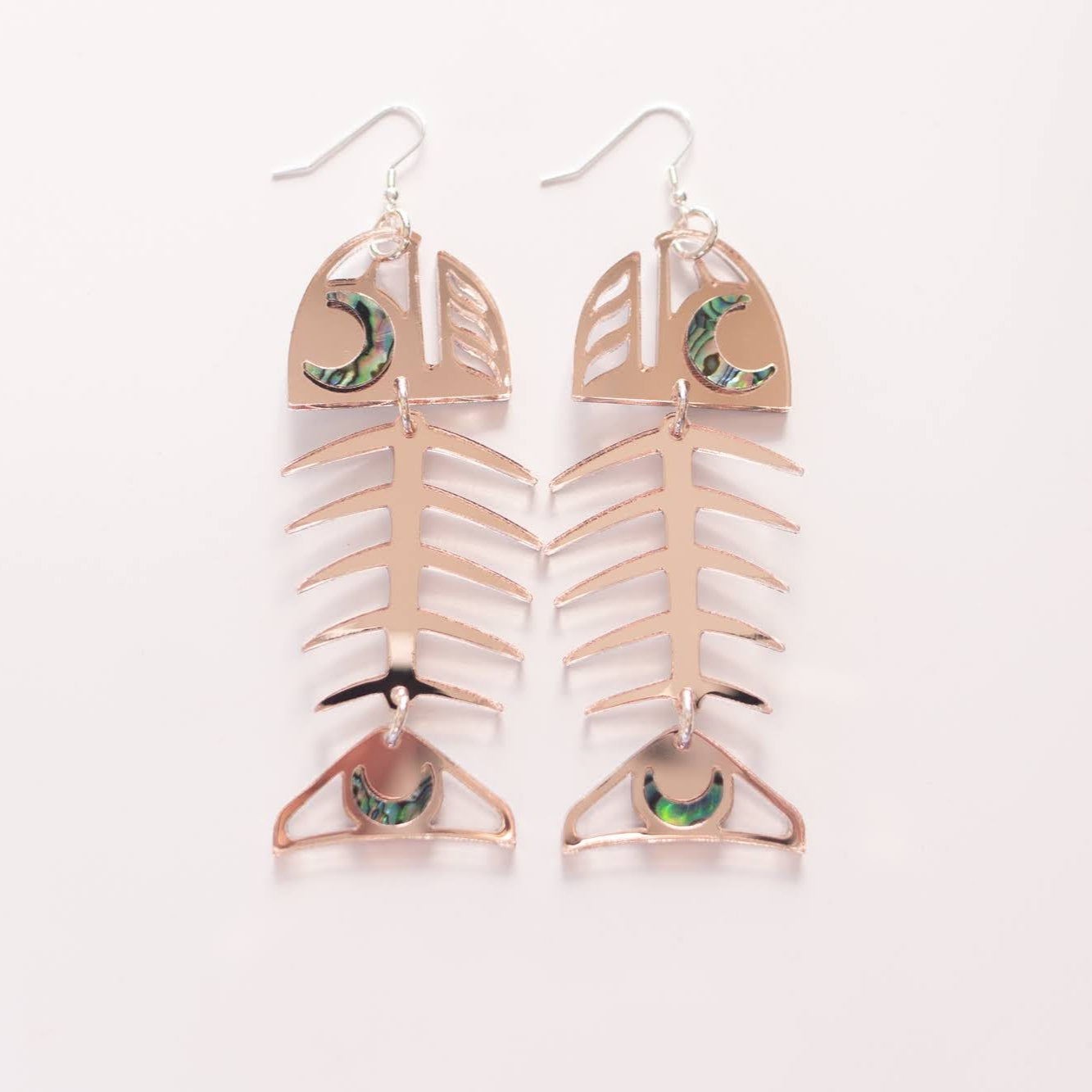 A pair of Medium Salmon Ghost earrings in rose gold mirror acrylic from Copper Canoe Woman.