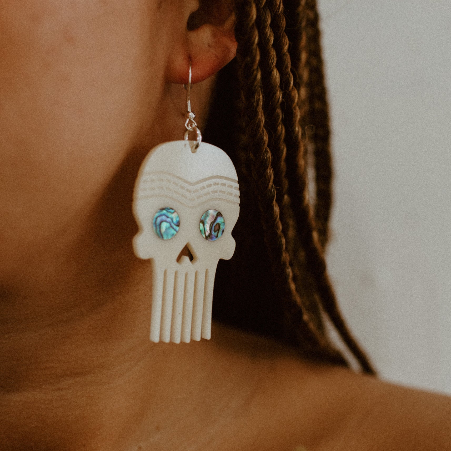 Closeup of model wearing the Skull Comb earring in ivory acrylic from Copper Canoe Woman.