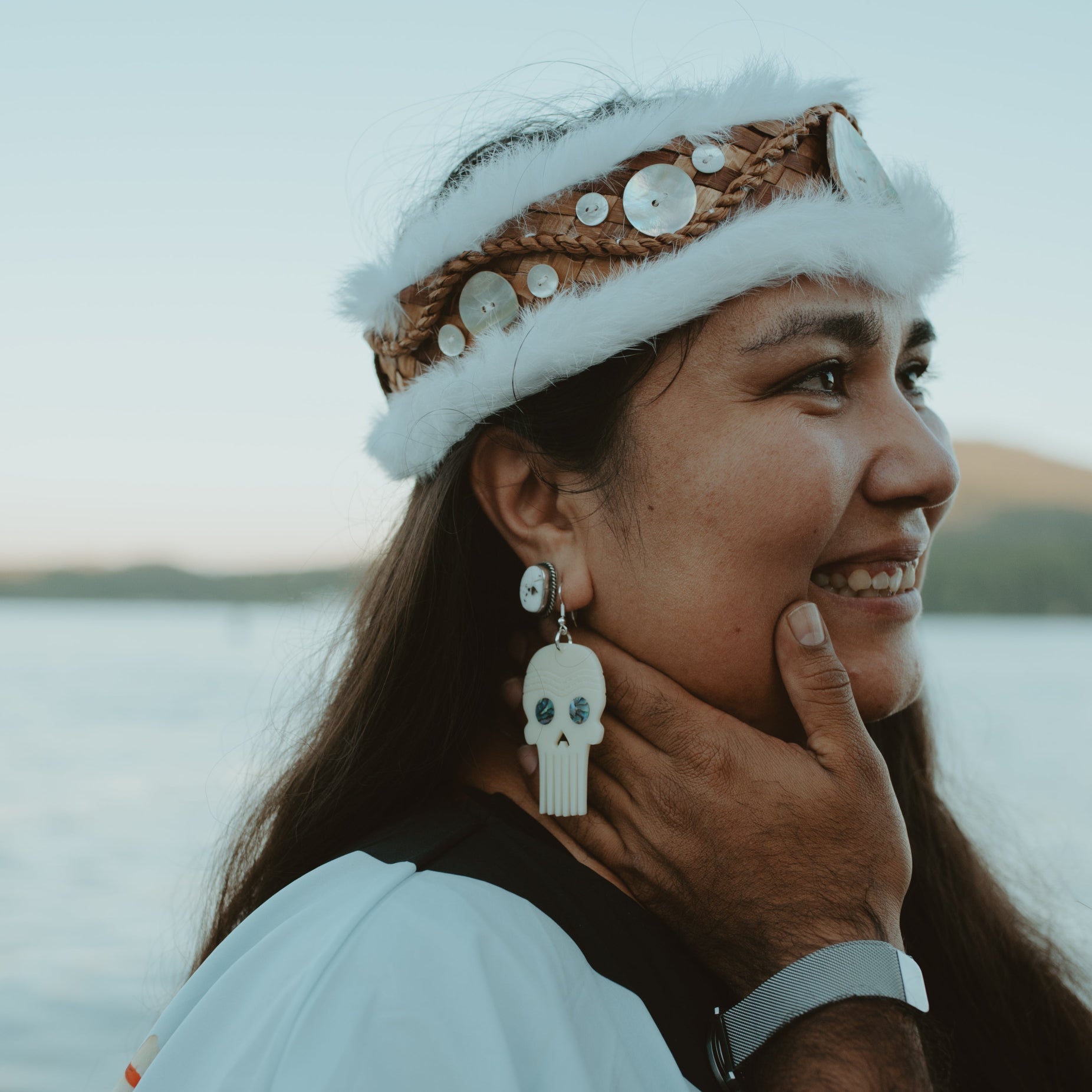 A woman stares at someone off camera while wearing a pair of Skull Comb earrings from Copper Canoe Woman in ivory acrylic.