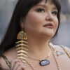 Vina Brown wearing large gold mirror acrylic salmon bone earrings.