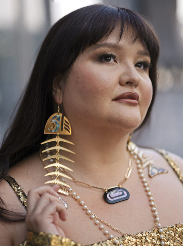 Vina Brown wearing large gold mirror acrylic salmon bone earrings.