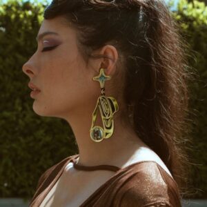 Model wearing raven earring in gold acrylic.