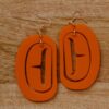 Orange ovoid formline earing on hooks with trigon cutout.