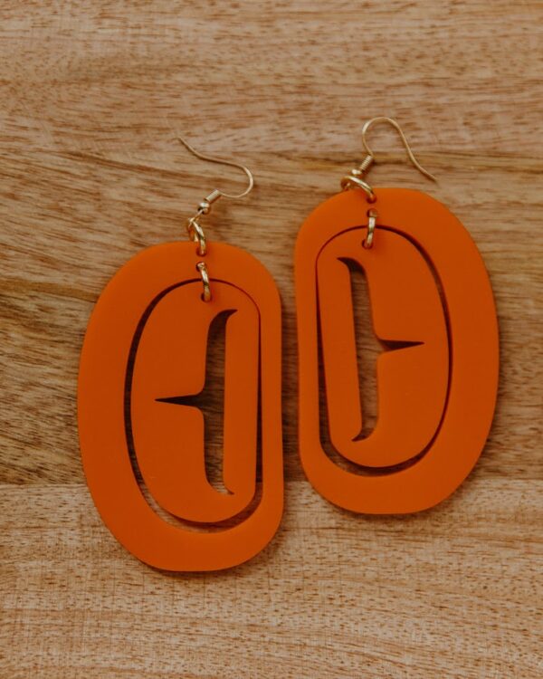 Orange ovoid formline earing on hooks with trigon cutout.