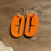 Orange ovoid earrings with trigon cutout.