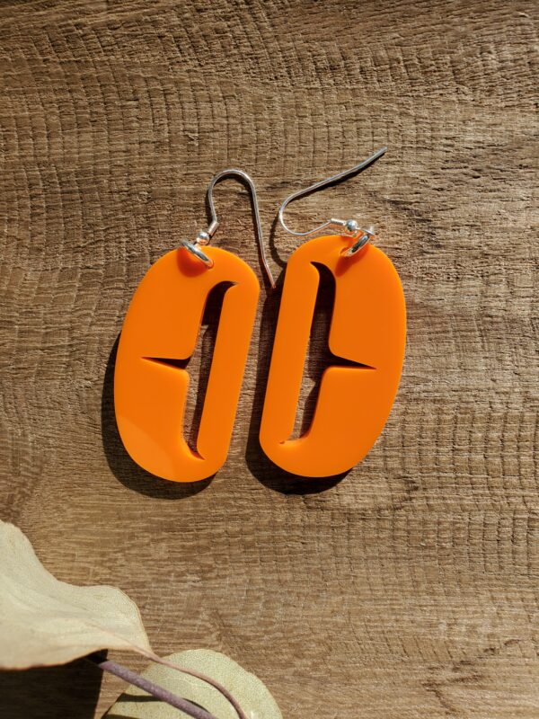 Orange ovoid earrings with trigon cutout.