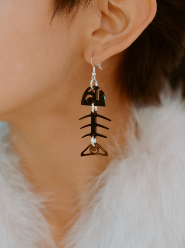 Model wearing small salmon bone earring in black acrylic.