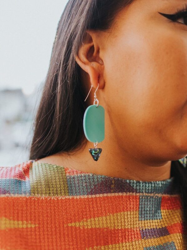 Model wearing ovoid earring with abalone drop gem.