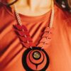 Model wearing owl eye style necklace in red on black acrylic.