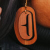 Close up of large ovoid earring in cedar wood with a trigon cutout.