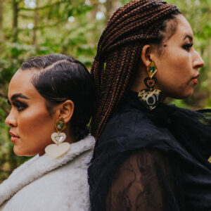 Two models wearing both color versions of Copper Canoe Woman's Monochrome Majesty earring.
