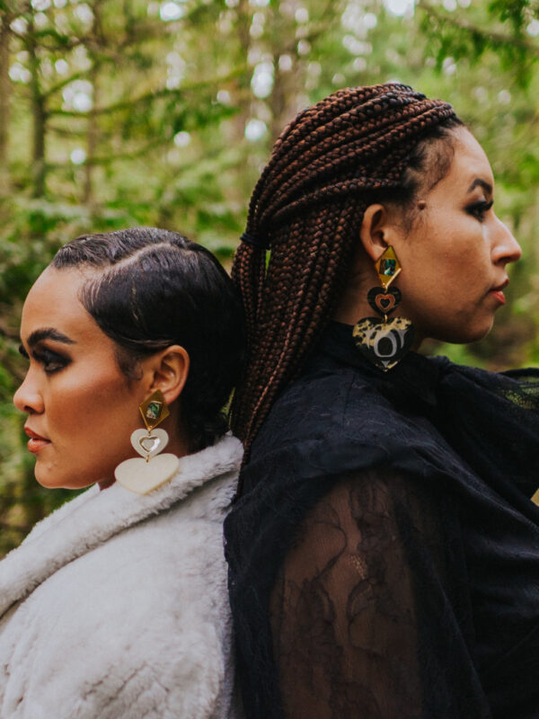 Two models wearing both color versions of Copper Canoe Woman's Monochrome Majesty earring.